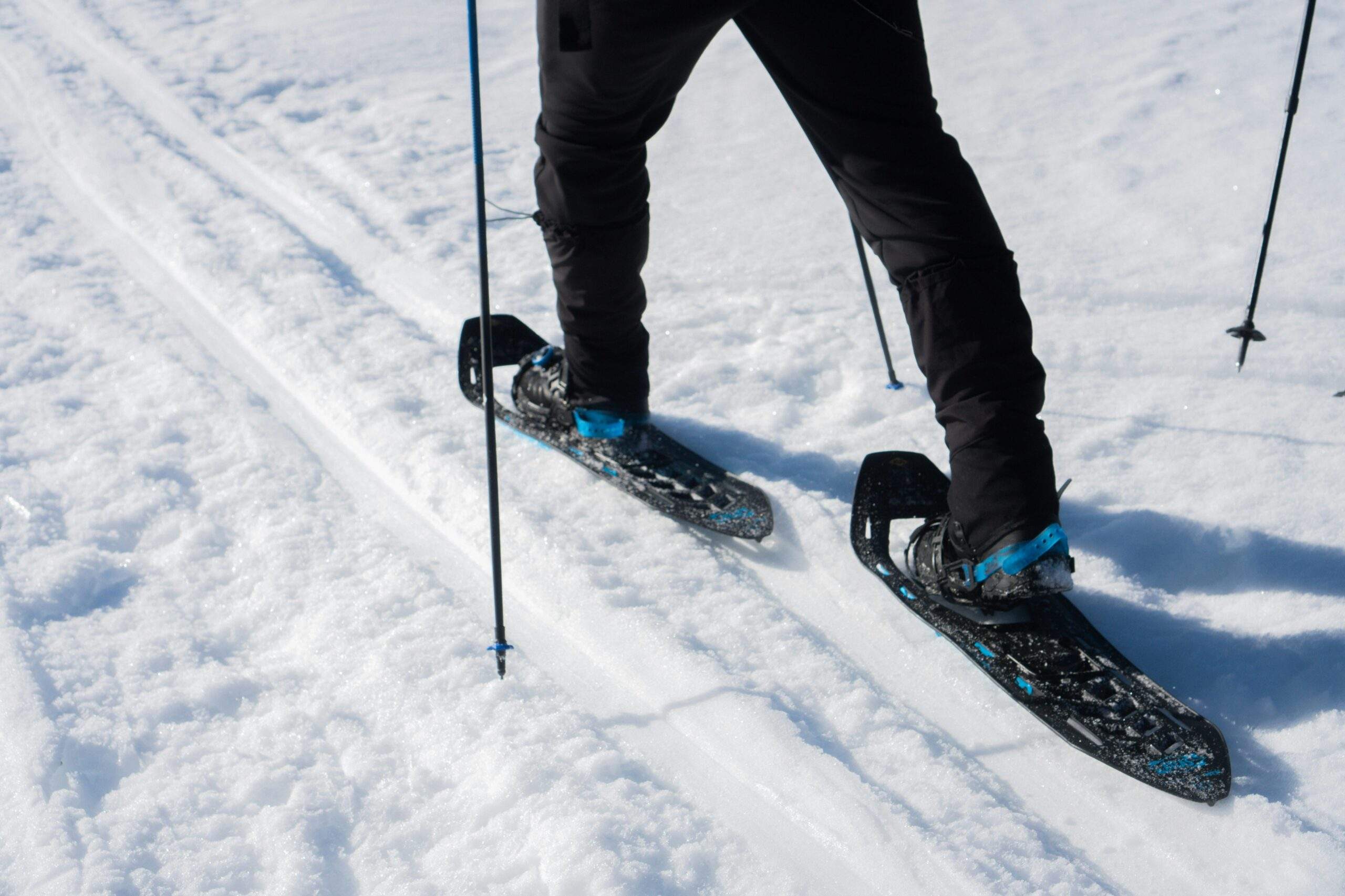 A hiker wearing insulated layers and holding trekking poles in snowy terrain