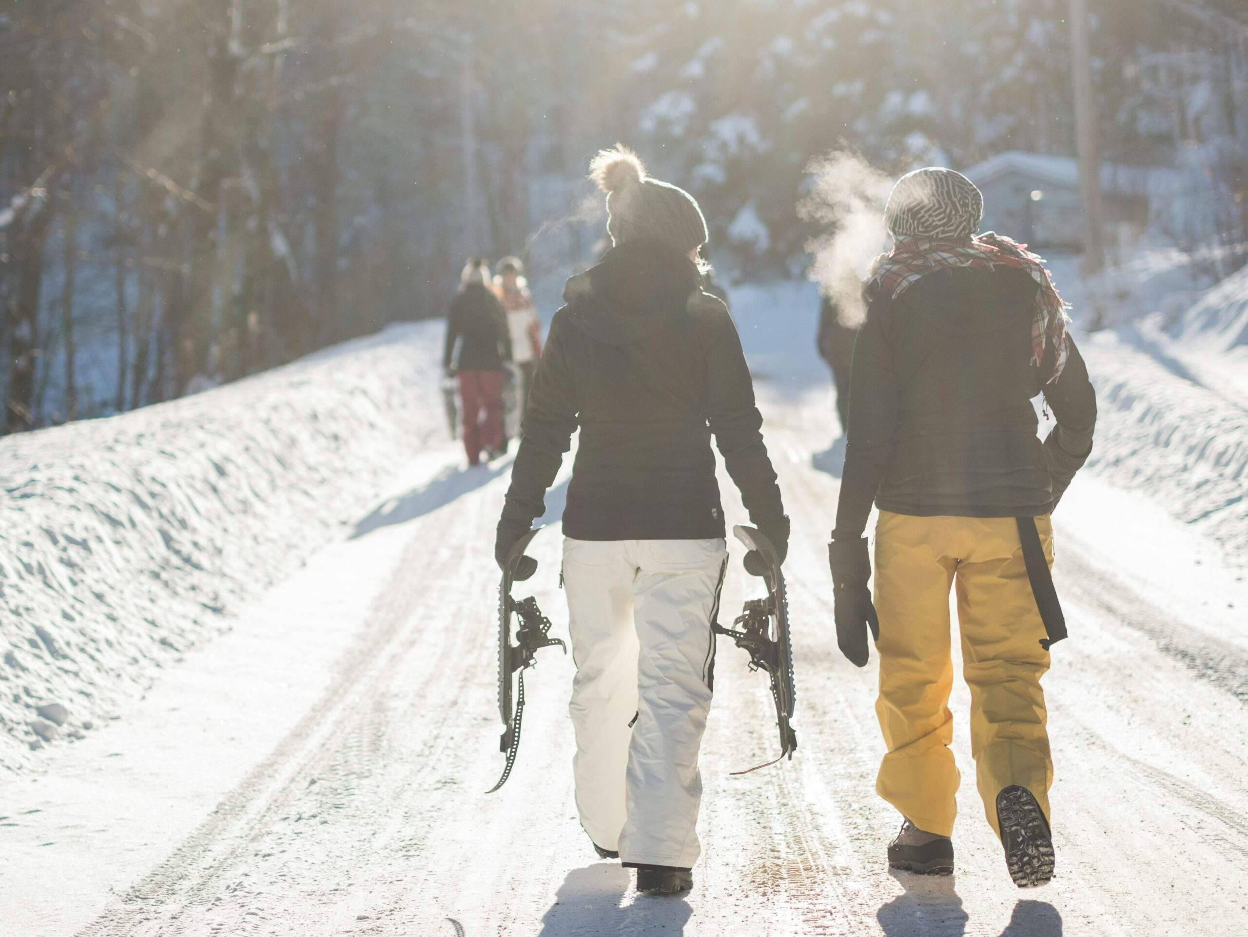 Smiling tourists enjoying snowshoeing and ice skating together