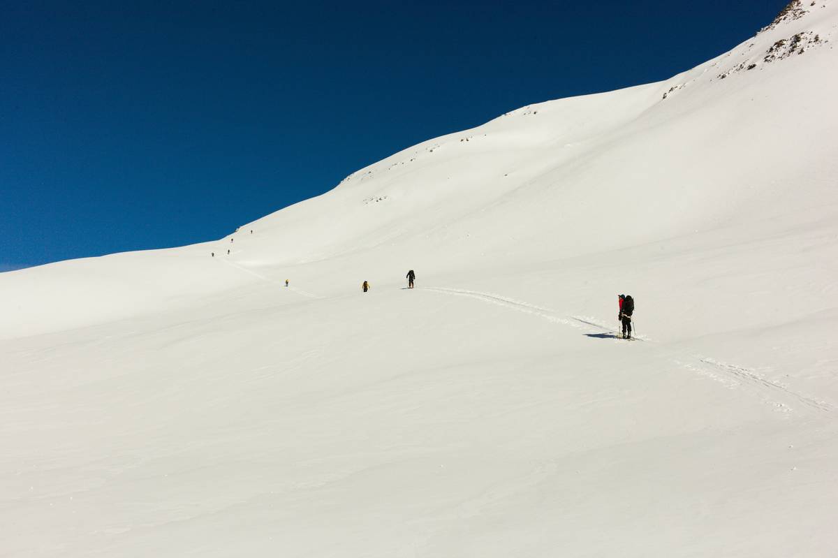 Smiling couple posing with mountains covered in fresh snow behind them.