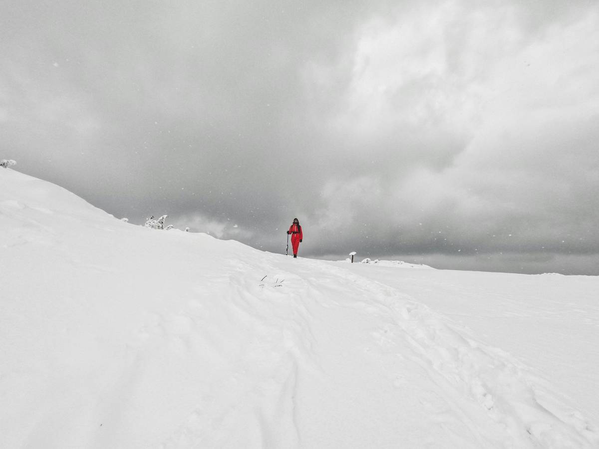 Person trekking across a snowy trail in bright sunlight