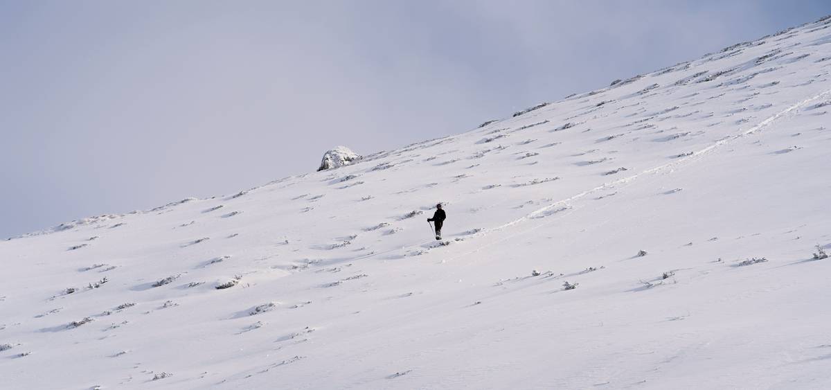 Sarah smiling at the top of a snow-covered mountain during dusk.