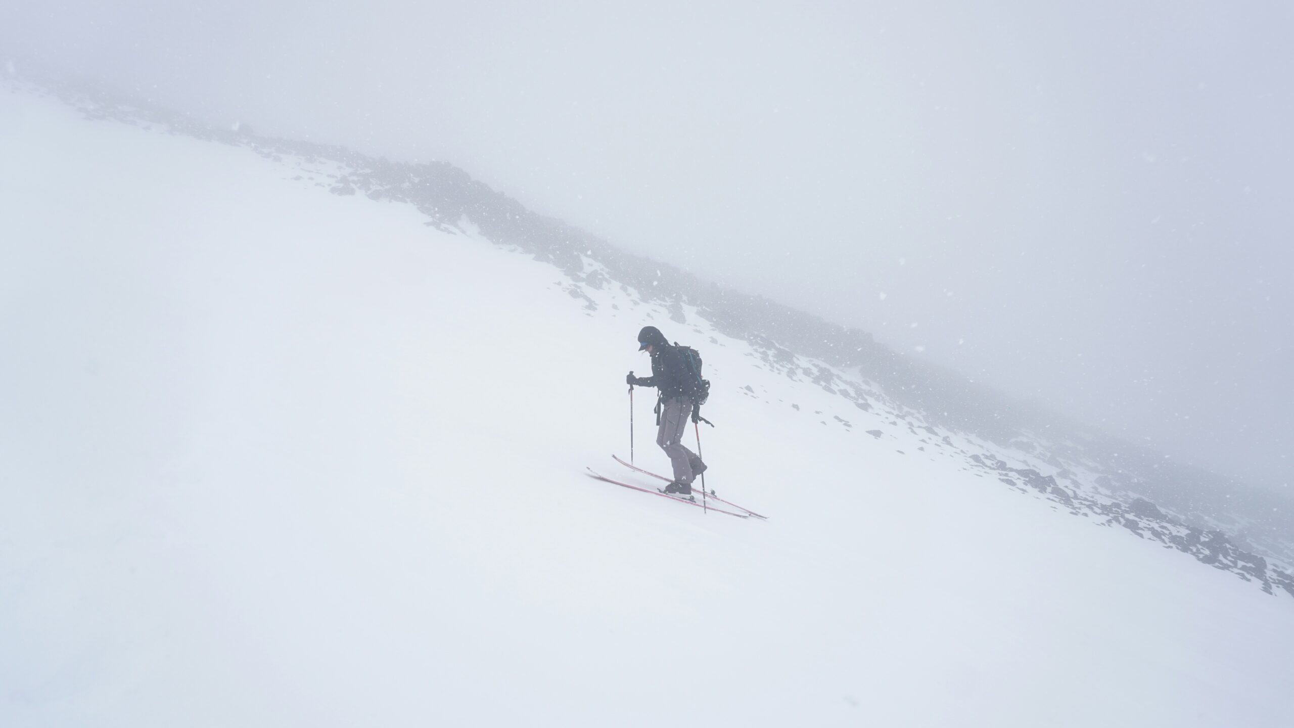 A person walking up a snowy hill on skis