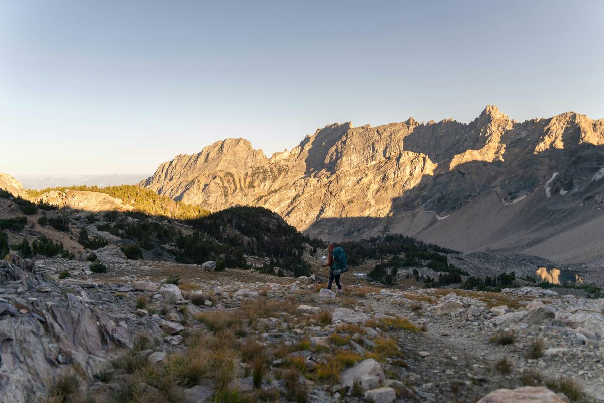 A person wearing snowshoes standing in front of a serene alpine valley covered in deep snow.